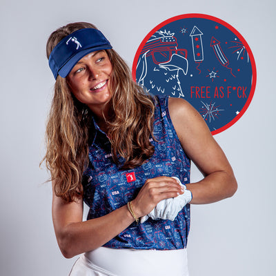 A smiling woman in a blue USA golf visor and the 'Merica - Navy - Women's Polo stands with arms crossed before a red circle featuring a patriotic eagle with sunglasses, fireworks, and the phrase “FREE AS F*CK” in white letters.