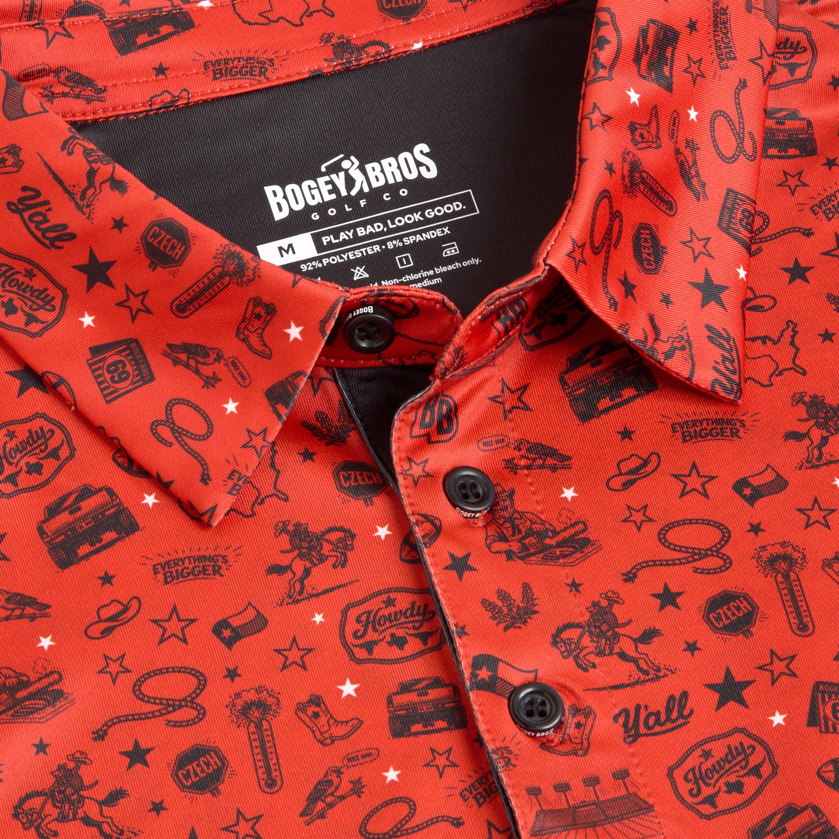 A close-up of a red Bogey Bros polo shirt with black Western-themed illustrations, including cowboys, cacti, boots, lassos, stars, and words like Howdy and Yall. The shirt label and three black buttons are clearly visible.