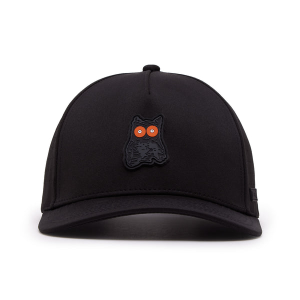 The Night Owl - Performance Golf Hat - Snapback is a black cap with a small cartoon black owl patch with bright orange eyes above the brim, made from sweat stain resistant material with a curved bill and visible stitching on white background.