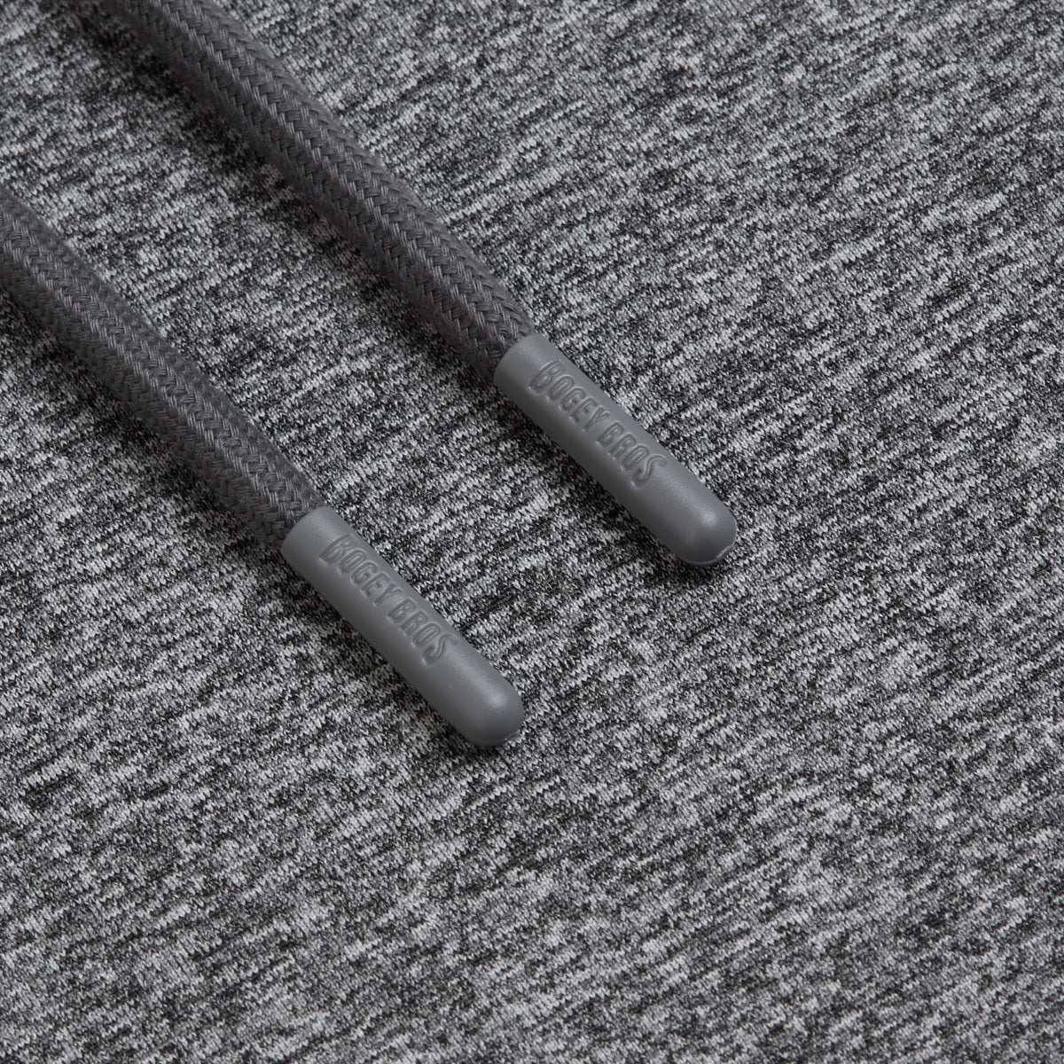 Two charcoal gray shoelaces with plastic aglets, each embossed with LACE LEADS, rest on a Heather Gray - Hoodie. The even lighting highlights the moisture-wicking texture of both the hoodie’s heathered fabric and the laces.