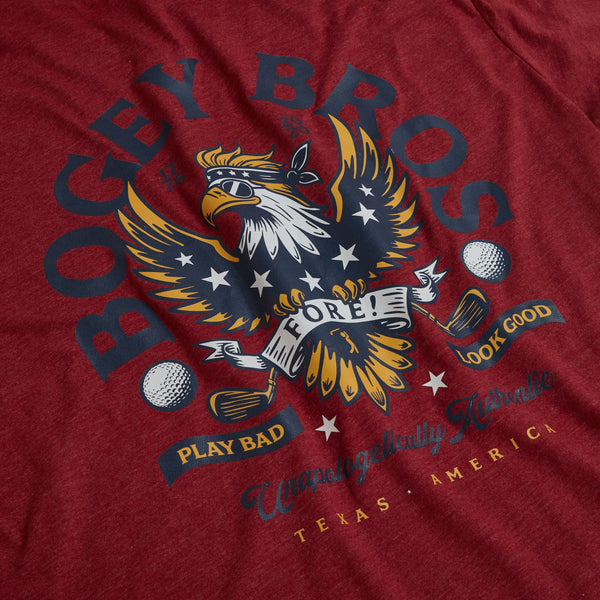 The FREEagle - T-Shirt is maroon with an eagle graphic holding golf clubs and balls. Featuring an athletic fit, it displays "BOGEY BROS, FORE!, PLAY BAD, LOOK GOOD," and "Unapologetically Average, Texas, America.