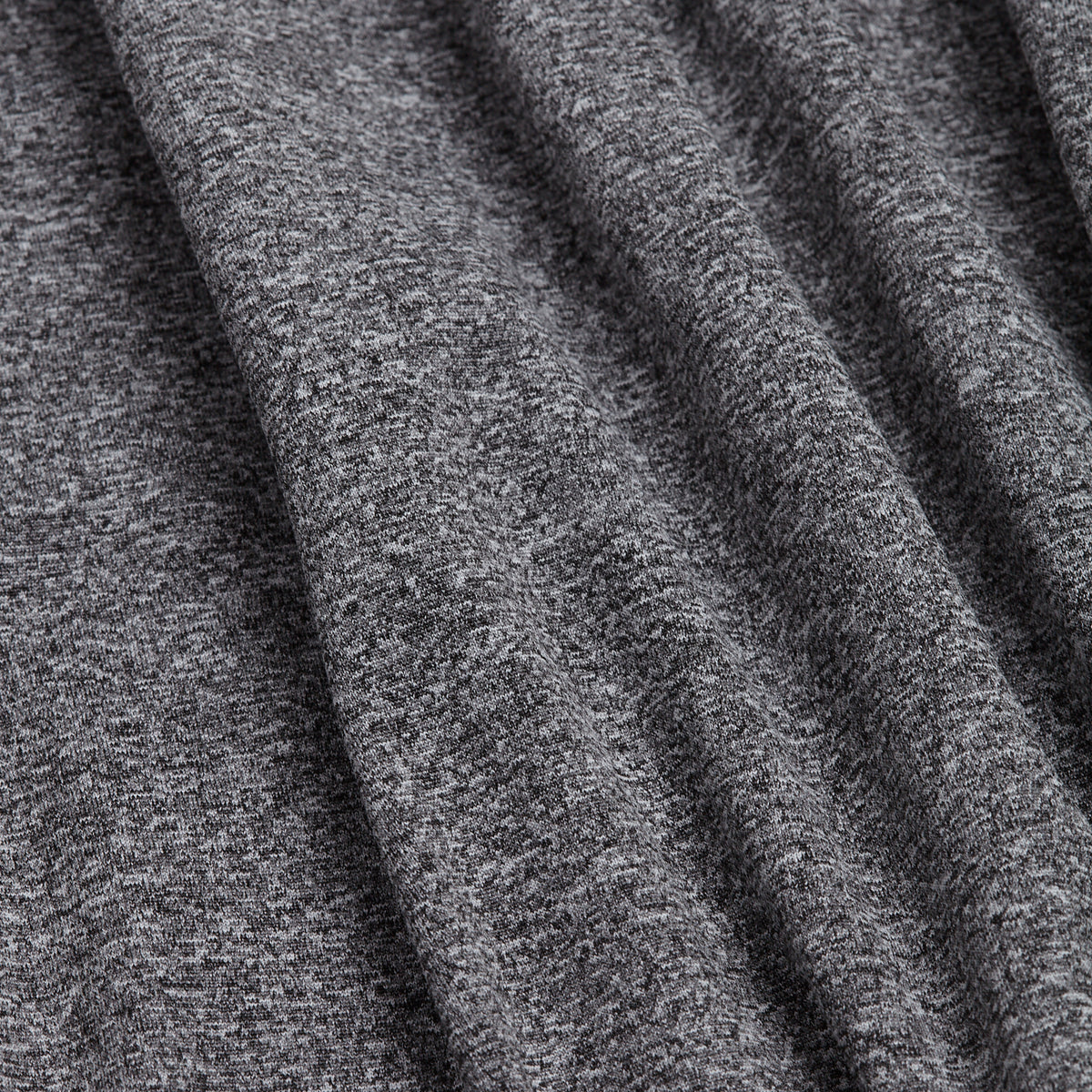 Close-up of the Heather Gray - Hoodie’s jersey knit fabric. The material showcases a fine, speckled blend of dark and light gray fibers for a textured look. Draped in soft, vertical folds, the hoodie’s flexible and stretchy athletic textile offers a smooth-touch feel with an athletic fit that ensures comfort during movement.