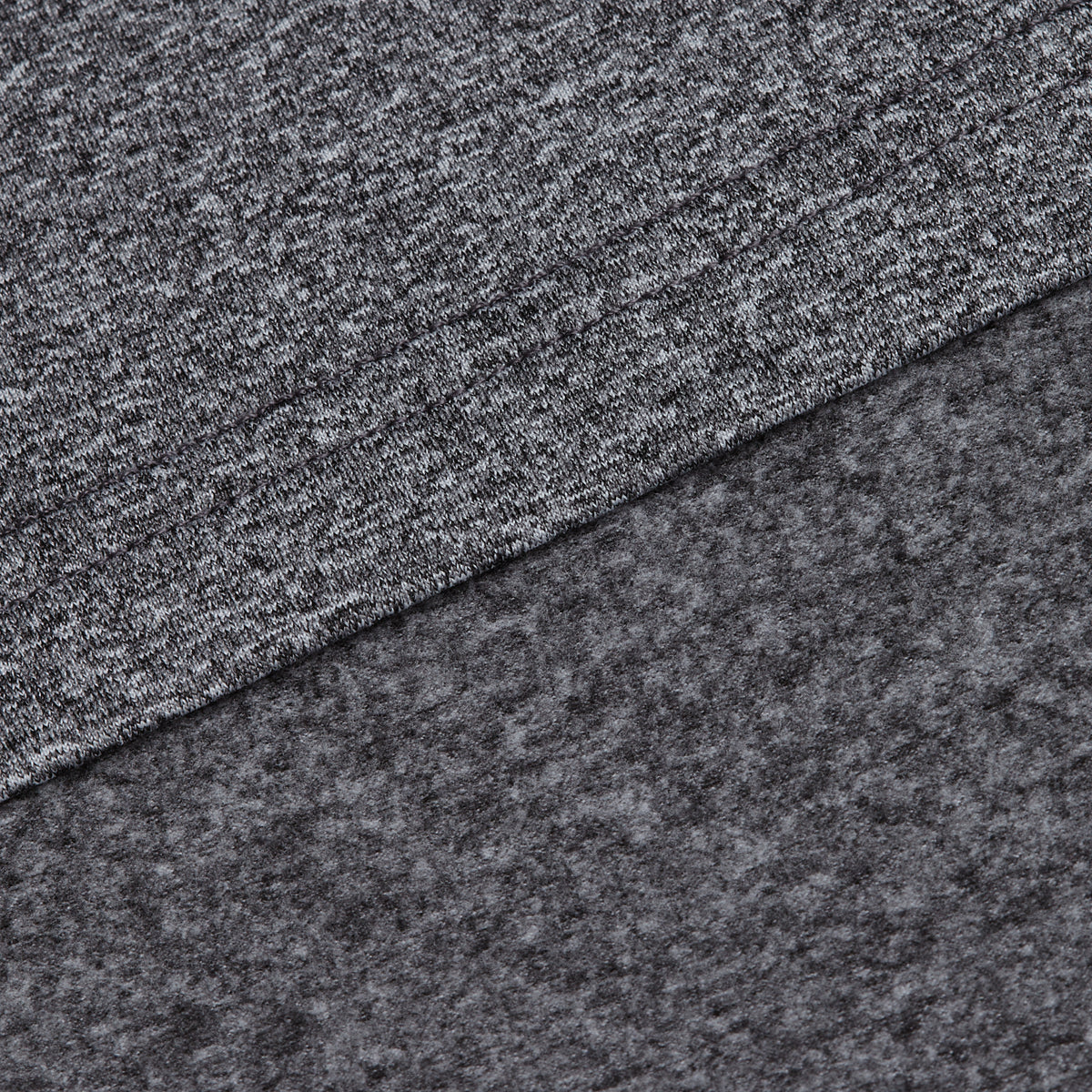 A close-up of two layers from the Heather Gray - Hoodie showcases the fabric’s features. The top layer reveals a smooth, knit texture, while the bottom layer is softer and fuzzier, likely indicating it is fleece. Renowned for its moisture-wicking properties, this fabric keeps you comfortable during any activity and makes the hoodie ideal for activewear. Both fabrics are arranged diagonally across the image.