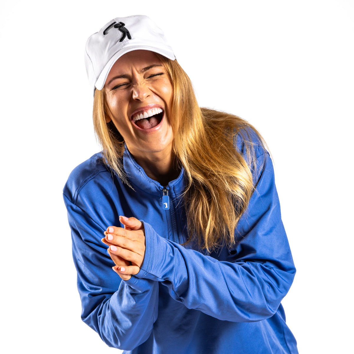 A woman with long blonde hair wears a white cap and the Cooler Blue - Q-Zip jacket, which features an athletic fit. She is laughing heartily with her eyes closed and hands clasped together in front of her against a plain white background.