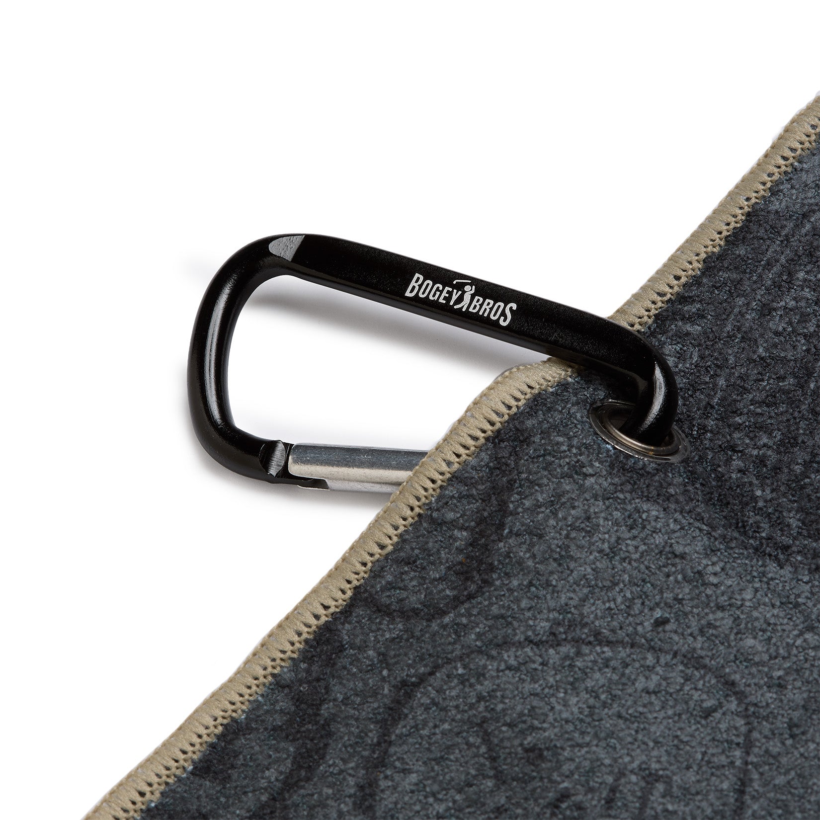 A black carabiner labeled BOGEY BROS clips through a metal grommet in the corner of a gray fabric with beige stitching on the edge. The fabric appears to be a towel or blanket.
