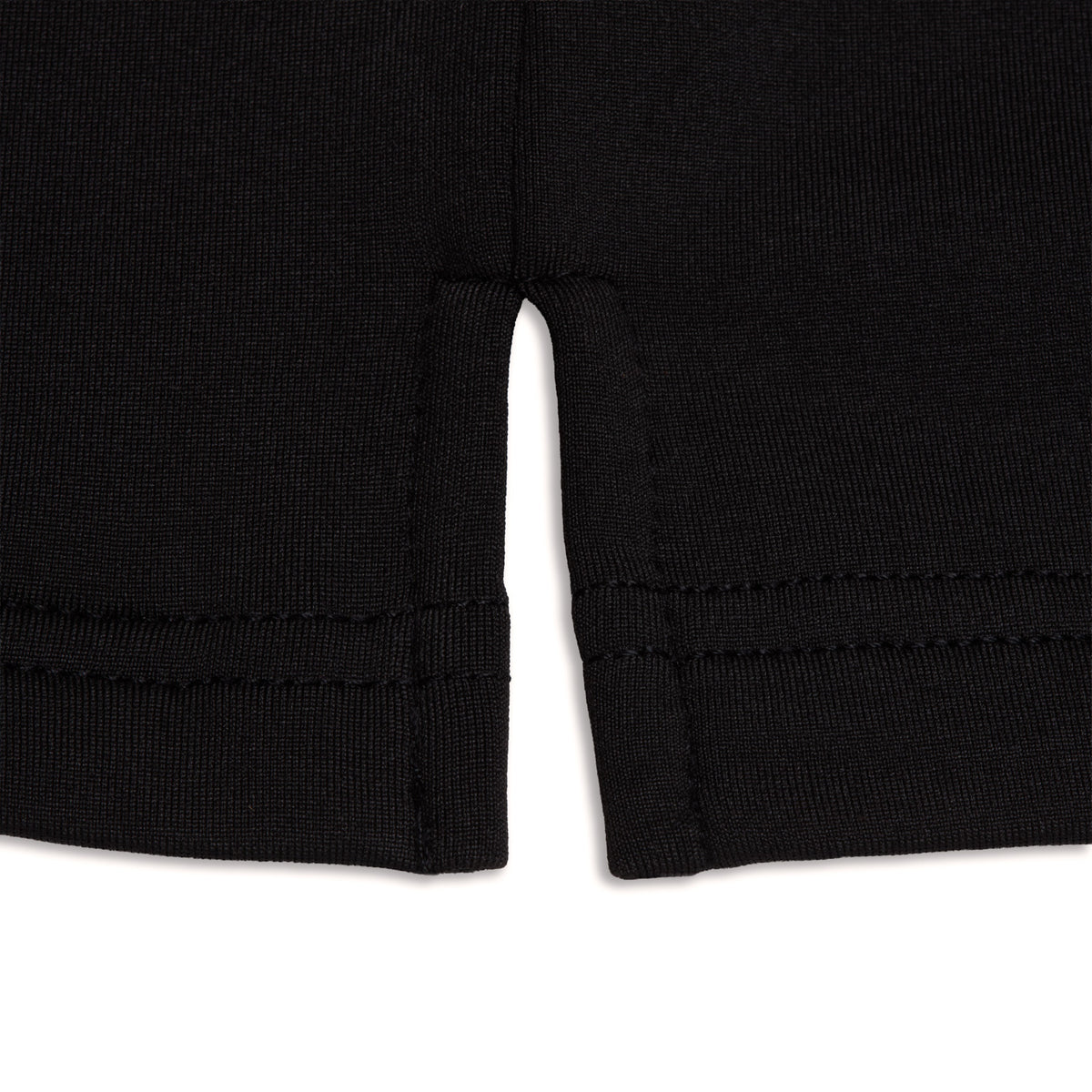 Close-up of the Black - Hoodie, a black fabric garment featuring a center slit at the hem. The material has a ribbed appearance, with visible stitching along the bottom edges and around the slit for a finished and durable construction. Designed with moisture-wicking properties, this hoodie ensures you stay comfortable and dry during active days. The background is white.