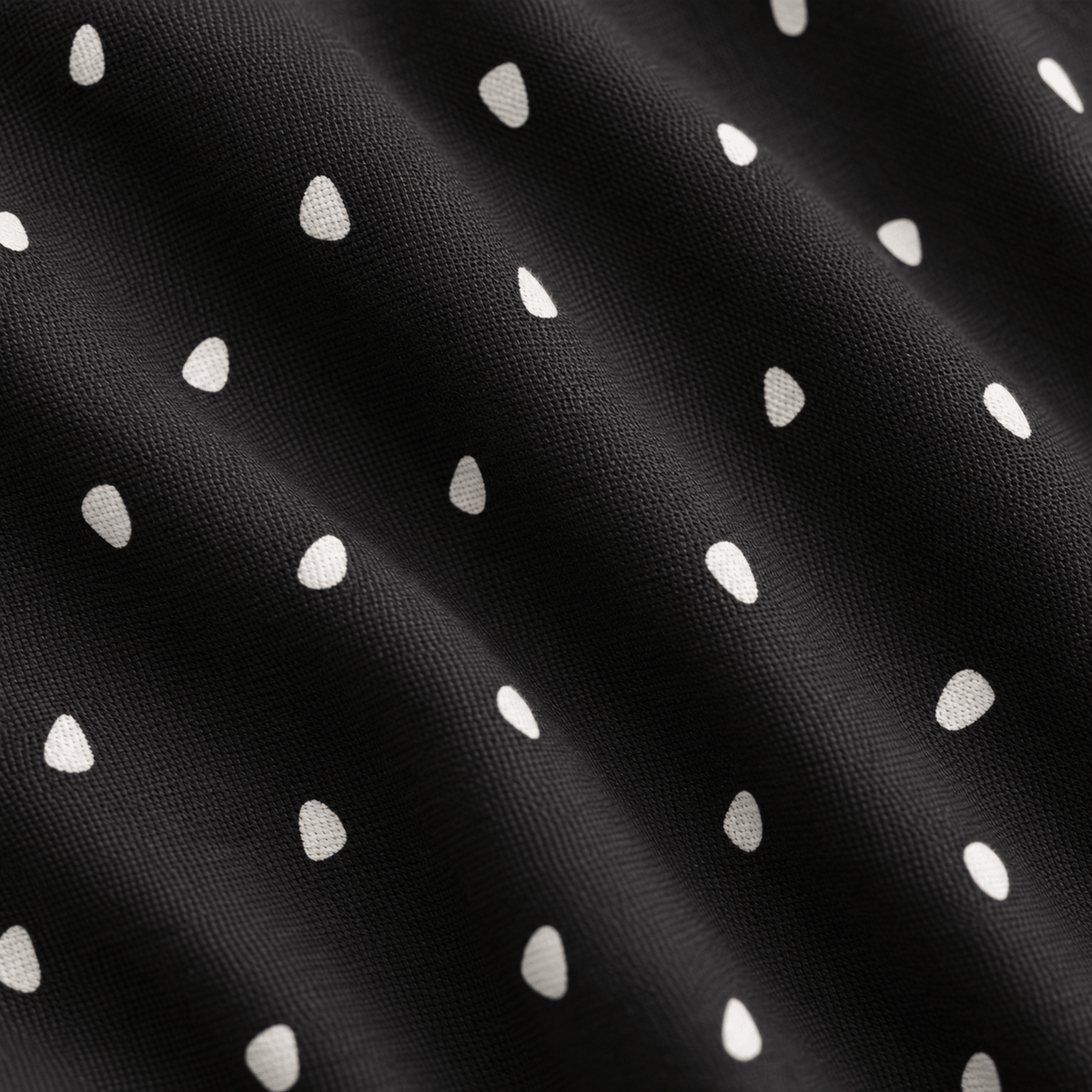 A close-up of the Dingleberry Doodles - Polo reveals dark, fine-woven fabric with a subtle, rippled texture. The material showcases a repeating pattern of small, off-white teardrop-shaped spots arranged in diagonal rows against a black background. Engineered for comfort, the polo’s advanced moisture-wicking properties keep you cool and dry while highlighting gentle folds and uniform design elements across its innovative cloth.