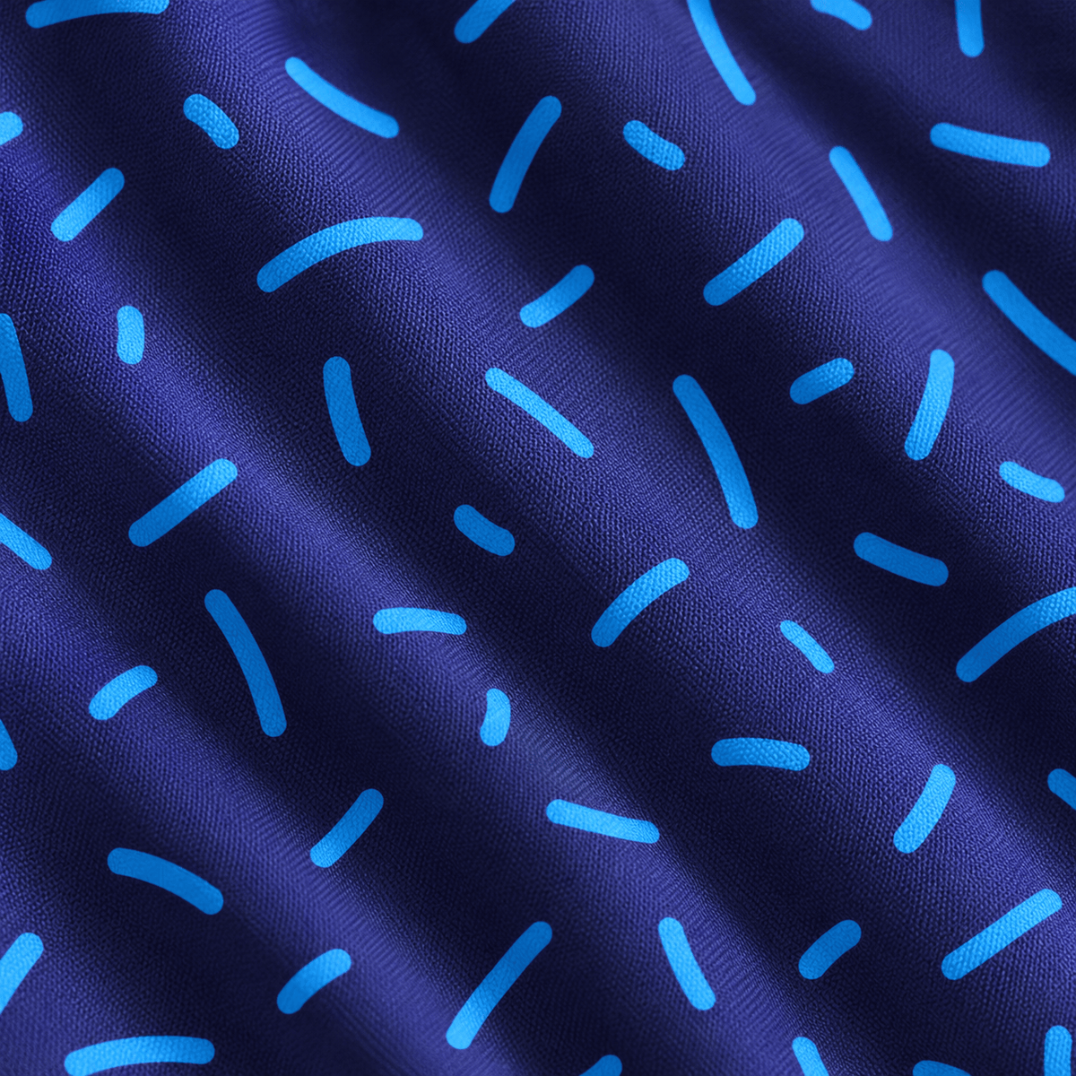 A detailed close-up of the Navy Niblets - Women’s Polo showcases dark blue fabric adorned with a lively pattern of scattered light blue curved lines. Gentle folds on the surface highlight its realistic texture, evoking depth and softness. Designed with moisture-wicking properties, this playful and non-uniform pattern offers comfort and versatility—perfect for active settings.