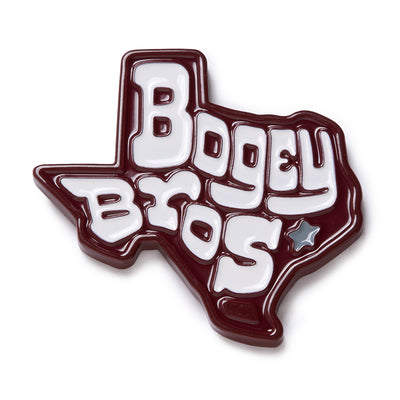 A glossy pin shaped like Texas features bold, white, stylized text reading “Bogey Bros” outlined in maroon, with a small silver star on the right side near the word “Bros.”.