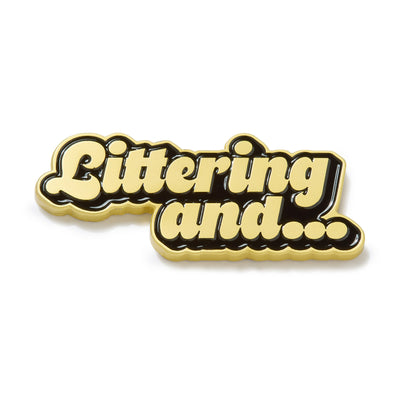 A gold-outlined ball marker features bold, black-shadowed text reading “Littering and...” in a playful script on a crisp white background. This unique accessory—titled “Littering and... - Ball Marker”—boasts iron nickel plating for extra durability and a brilliant finish.
