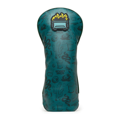 The Desert Golf - Driver Headcover is made of premium teal PU leather, embroidered with cacti, snakes, skulls, and garbage cans, “BOGEY BROS.” text, and features a top patch of a stylized toaster with yellow flames above it.