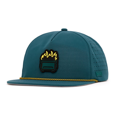 The Dumpster Fire - Unstructured Flat Bill Hat - Snapback features teal performance fabric, a gold chain accent, black patch with a burning couch graphic, perforated sides, and a small rectangular tag—making this snapback both stylish and unique.
