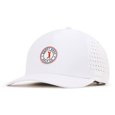 A white baseball cap with a curved brim, featuring a round, red, blue, and white embroidered “Bogey Bros Golf Co.” patch on the front. The sides have small ventilation holes, and there is a small rectangular tag on the side of the brim.