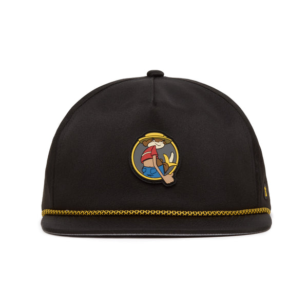 A black hat with gold trim at the brim features a cartoon character patch on the front, showing a smiling person in a hat holding up three fingers. The hats material appears smooth, and its shape is rounded without a visible brim.