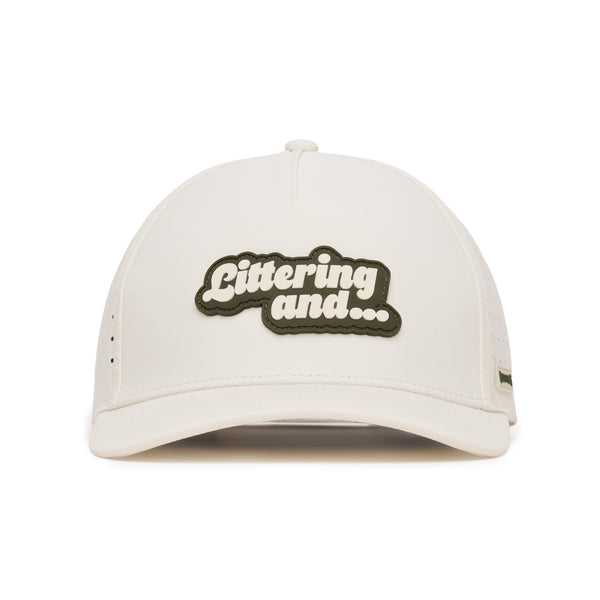 A white baseball cap viewed from the front, featuring a black and white patch in the center with the text Littering and... in bold, rounded letters. The cap has minimal visible detailing and clean lines.