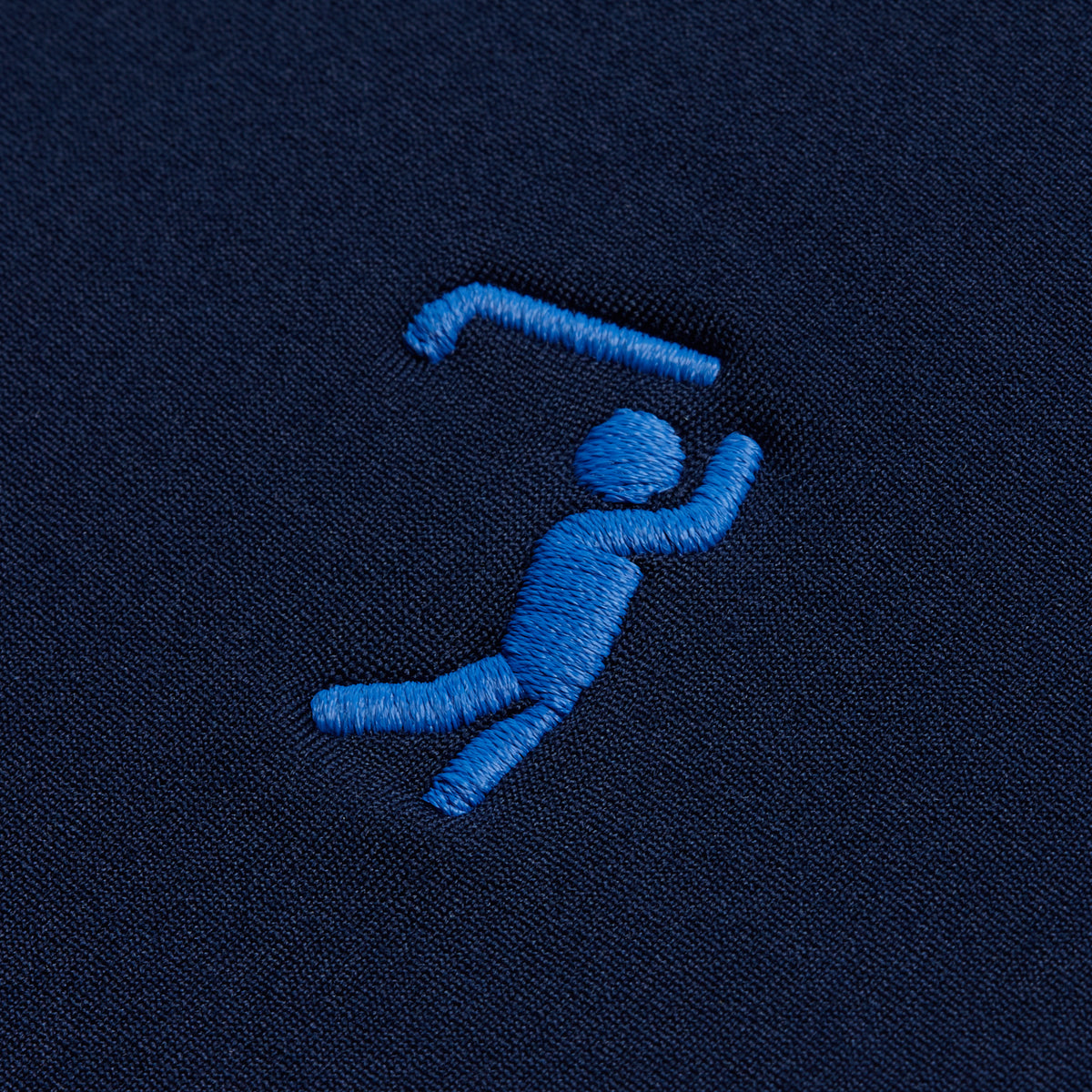 A blue embroidered figure on dark navy fabric, mid-swing with a golf club above the right shoulder—one arm bent, legs apart, capturing the dynamic motion of a golfer. This minimalist and stylized design features simple, solid shapes, making it a standout detail on our Navy Hoodie—perfect for elevating your athletic style on and off the course.