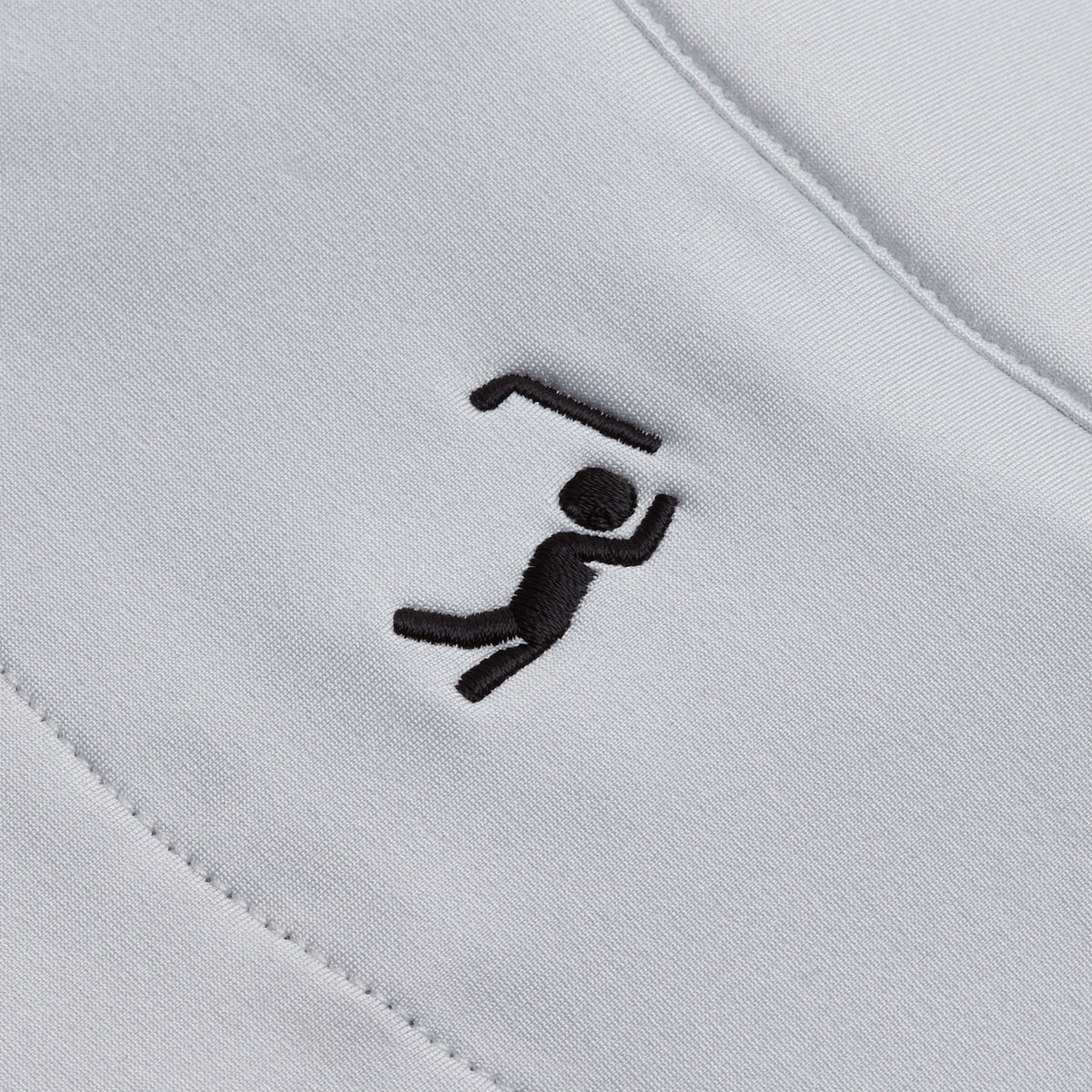A playful black stick figure holding a bent object overhead is smoothly embroidered on the light gray, moisture-wicking Bone - Q-Zip. The design features visible seams and maintains a simple, abstract style with precise stitching.