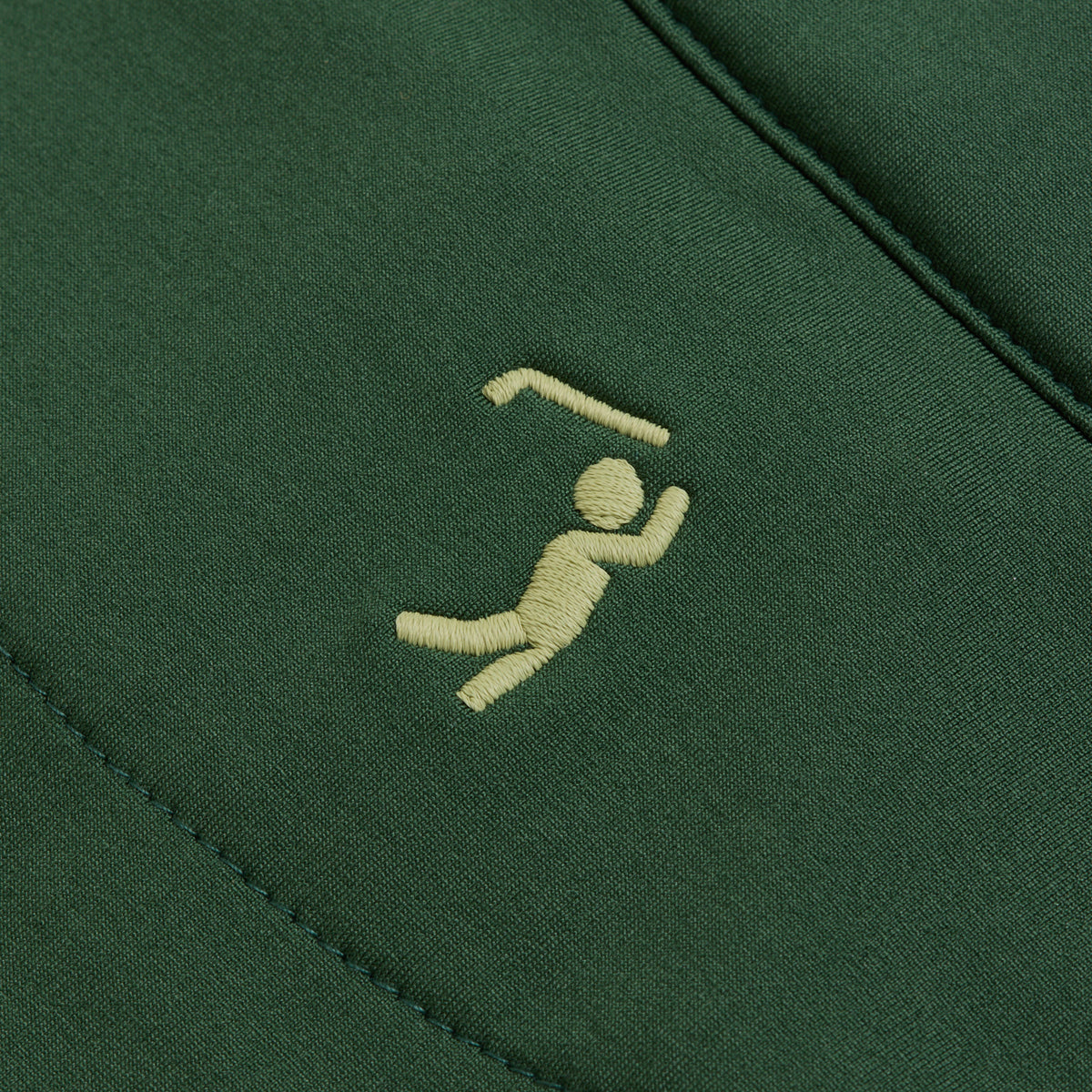 A yellow embroidered icon decorates the Forest Green Q-Zip, featuring a simple, dynamic figure with one arm raised under a bent line—an abstract nod to movement or activity. Crafted from super-stretchy fabric, this piece guarantees optimal comfort and freedom of movement for any occasion.