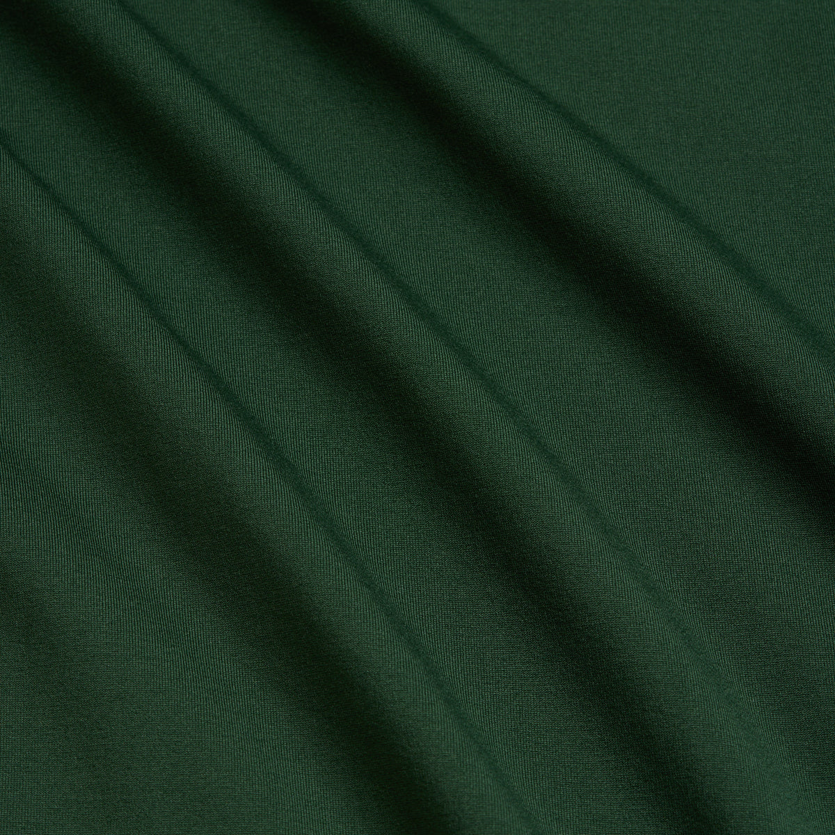 Smooth, forest green fabric with visible diagonal folds, creating soft shadows and highlights. The texture appears slightly stretchy and uniform in color throughout the image, indicating it is likely a type of jersey or knit material used in the Forest Green - Hoodie.