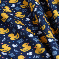 The Big Duck Energy - Polo features a navy blue fabric with yellow rubber ducks, small white ducks, duck outlines, bright confetti shapes, and playful “BIG DUCK ENERGY” and “B.D.E.” text. Athletic fit for comfort; gently wrinkled finish.