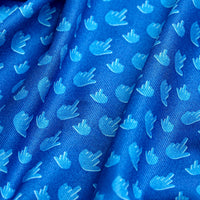 A close-up of the Bogey Bros Birdie Finger - Blue Jay - Polo shows blue, moisture-wicking, ribbed fabric with a repeating pattern of lighter blue hand shapes. Folds in the material create dynamic shadows and highlights.