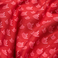 Close-up of Birdie Finger - Robin - Polo’s red fabric features a subtle, repeating pattern of small pink tulip-like shapes. Gentle folds highlight its sheen and texture, while moisture wicking keeps you comfortable.