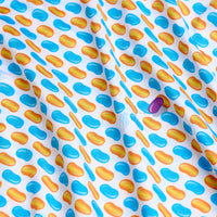 A close-up of the Flickin' Beans - Polo shows a repeating pattern of blue and orange ovals on white, with one standout purple oval. The slightly wrinkled fabric features an athletic fit and a textured surface for added visual interest.