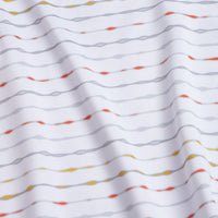 The Heat Index - Polo features white fabric with a subtle wavy texture, horizontal gray lines, and scattered orange, yellow, and red dashes. It offers UPF 50 protection plus an athletic fit with soft folds for a modern look.