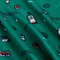 The Meister - Polo features green, super stretchy fabric printed with diagonal Jägermeister-themed illustrations—bottles, hats, shot glasses, and “Jägermeister” in black—plus visible folds and highlights.