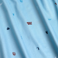 The Port - Polo features light blue, soft-textured fabric with an athletic fit, moisture-wicking properties, and small embroidered golf-themed icons like lobsters, sailboats, golf clubs, plus red BOGEY BROS text scattered throughout.