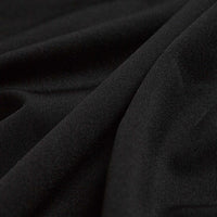 Close-up of Smooth Black - Polo fabric with diagonal folds. The fine, slightly reflective texture features soft shadows, gentle draping, moisture-wicking properties, and a subtly visible weave—likely made of cotton or polyester.