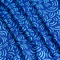 A close-up of Arcs - Blue - Polo fabric shows a wavy, abstract pattern of curved turquoise lines. The slightly wrinkled, moisture-wicking material adds texture and depth while keeping you comfortably dry.