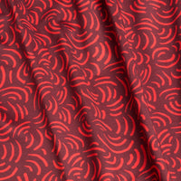 The Arcs - Red - Polo features a wavy abstract pattern of curved red lines on a dark red background, with visible folds for texture and built-in moisture wicking for added comfort and functionality.