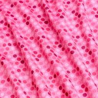 The Dots - Pink - Polo features soft, moisture-wicking pink fabric with small, scattered dots in shades of pink and red. Gentle folds create subtle shadows and highlights, adding depth and texture to the design.