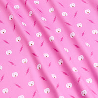 The Shocked - Polo features a pink fabric with white electrical outlets and magenta lightning bolts in a diagonal pattern. Its athletic fit and moisture-wicking design offer comfort, while soft folds enhance its playful, whimsical look.
