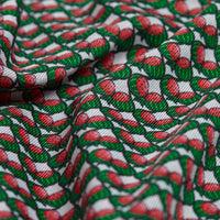A close-up of the Wantermelons - Polo fabric shows a repeating red oval pattern with green and black outlines on a white, slightly wrinkled background. Its moisture-wicking material adds texture, depth, and enhanced comfort.