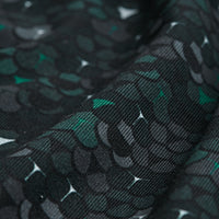 Close-up of the Whale Tail - Snake Skin - Polo fabric, showcasing a scale-like pattern in dark green, black, and white. The curved, overlapping shapes resemble reptile scales and the material offers moisture wicking for comfort and breathability.