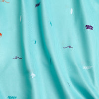 The Beach - Women's Polo features aqua blue fabric with scattered wave and palm tree prints, plus 