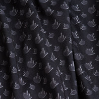 The Birdie Finger - Raven Women's Polo features black fabric with a slight sheen, decorated with small white hand symbols. It has a subtle texture, visible folds, and provides moisture wicking for comfort.