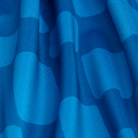 Close-up of Checked Out - Women's Polo in blue, displaying a wavy checkerboard pattern with various blue shades. Soft folds, vertical creases, and a subtle sheen highlight its moisture-wicking comfort.