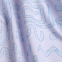 Close-up of light blue abstract wavy and geometric lines on the Dipsy Doodle - Women's Polo; the athletic-fit, white fabric's subtle wrinkles, moisture-wicking texture, and soft shadows highlight its quality and depth.