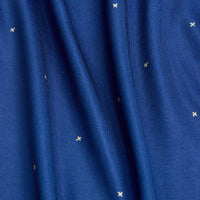 Close-up of Exes - Navy - Women's Polo shows blue, moisture-wicking fabric with soft vertical folds. Scattered pale yellow X-shaped stitches add a subtle star-like pattern. The smooth, slightly shiny material is perfect for activewear.