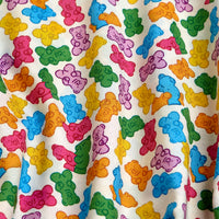 A closeup of the Gummy Bears - Women's Polo, featuring colorful gummy bear illustrations on moisture-wicking fabric with folds highlighting its playful white design.
