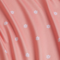 A close-up of In Bloom - Women's Polo shows pink fabric with a gentle drape, decorated with small white floral designs for a soft, delicate look and UPF 50 protection for sun safety.