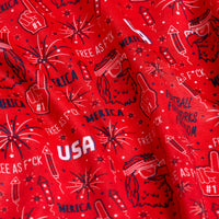 A close-up of 'Merica - Red - Polo: red fabric with white and blue patriotic designs—fireworks, rockets, #1 foam fingers, sunglasses, bold phrases—and UPF 50 protection for sun safety.