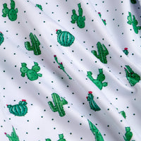 The Prick-Ly Pear - Women's Polo features white fabric with a repeating pattern of small green cacti—some with pink flowers—mixed with green dots. This slightly wrinkled polo also offers moisture-wicking comfort.