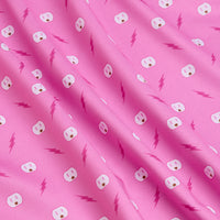 A close-up of Shocked - Women's Polo shows pink fabric with a playful repeat of white electrical outlet faces and pink lightning bolts. Athletic fit adds gentle folds, enhancing the textured, vibrant design.
