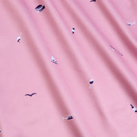 The Mixer - Women's Polo features pink fabric with a subtle vertical ribbed texture and small prints of boats, helicopters, wine glasses, seagulls, hats, and oars in white, black, and purple. Moisture wicking ensures all-day comfort.