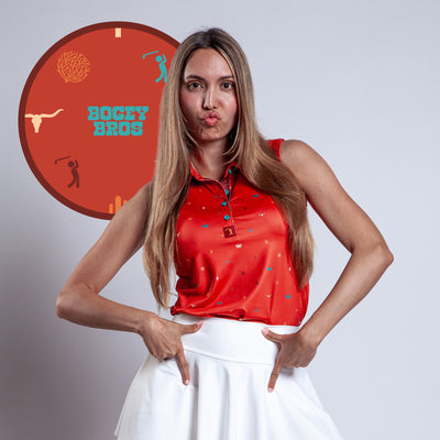 A woman with long, straight hair wears the athletic fit Desert - Women's Polo in red and a white skirt, making a playful pout and hand gesture. Behind her is a circular "BOGEY BROS" logo with golfer silhouettes on a red background.