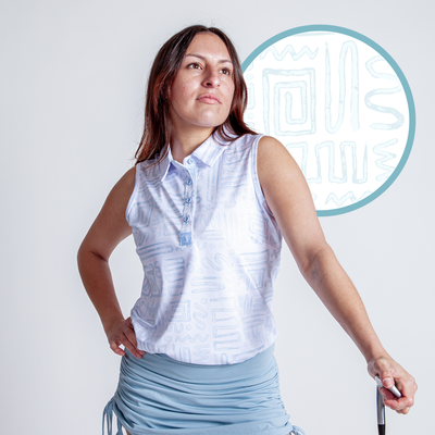 A woman with long brown hair wears the Dipsy Doodle - Women's Polo, featuring light blue abstract geometric patterns, paired with a light blue ruched skirt. She holds a golf club and gazes upward, showcasing the polo's athletic fit and stylish details.